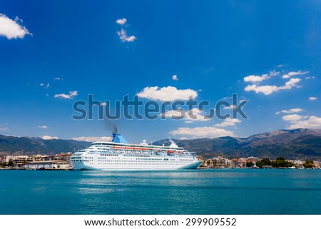 Big cruise ship anchored in port against a blue sky and clouds in Greece