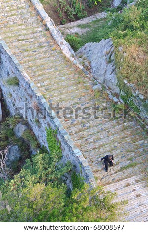 Monk in black robe walking up the stairs to the monastery