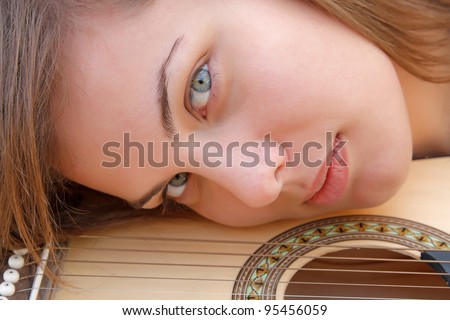 Young attractive woman\'s face next to guitar strings close up