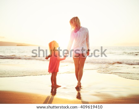 Happy mother and young daughter on the beach at sunset