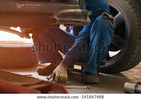 Selective focus low key  young man using tool  for repair brake car  a part of wheel tire in garage.