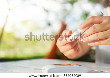 Close up of asian woman hands using lancet on finger to check blood sugar level by Glucose meter, Healthcare Medical and Check up, Medicine, diabetes, glycemia, health care and people concept