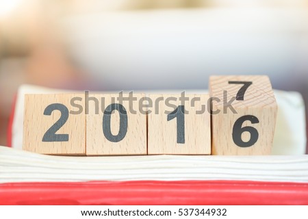 Wooden number block 2016 and 2017 on red book, for conuting End of Year and Happy New year day celebration background concept