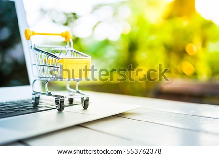 Small shopping cart / trolley on Laptop for shopping online with copyspace nature background, Technology online marketing and business trading concept.