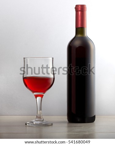 Glass of red wine grapes with bottle wine.