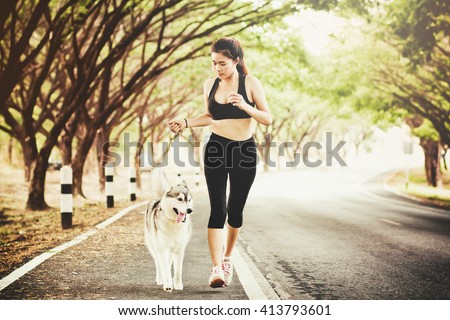 sport girl is running with a dog (siberian husky) at the morning on the road