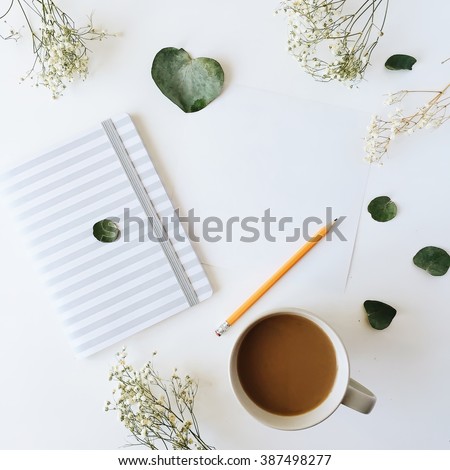 Cup of coffee with milk, sketchbook, pencil, green leaves and dried flowers. Overhead view. Isolated on white. Flat lay, top view