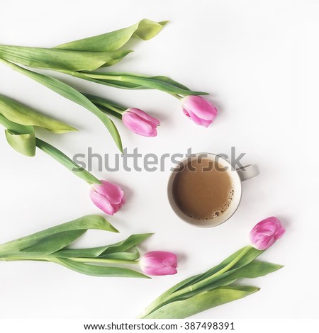 Overhead view of cup of coffee with milk and pink tulips isolated on white background. Flat lay, top view