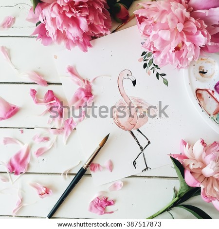 Workspace. Pink flamingo painted with watercolor, paintbrush and pink peonies isolated on white background. Overhead view. Flat lay