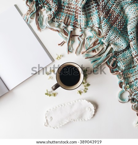 Cup of black coffee, white sleep mask, mint plaid, magazine and green leaves isolated on white background. Overhead view. Flat lay, top view