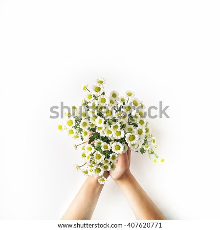 Chamomile bouquet in girl\'s hands on white background. Flat lay, top view