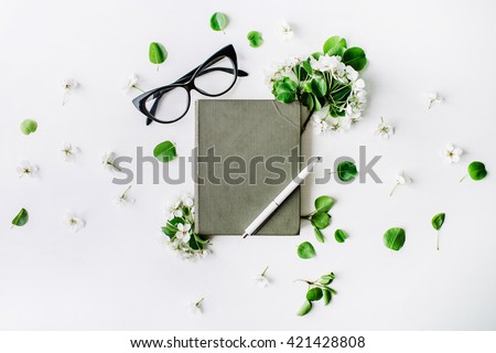 Glasses, old book, pen and branches with leaves and flowers on white background. Flat lay composition