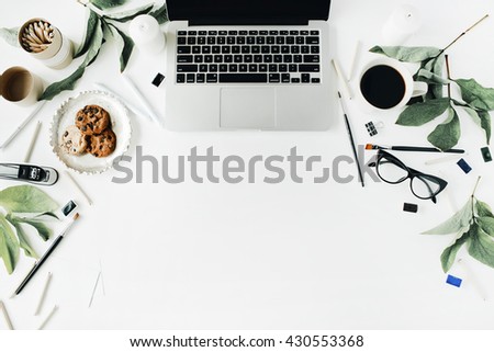 laptop, glasses, cup of black coffee, cookies on golden tray, pencils, paintbrushes and leaf. Flat lay composition for bloggers, magazines, social media and artists. Top view, home office workspace