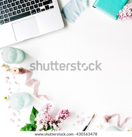 laptop, lilac flowers bouquet, spool with beige and blue ribbon, mint diary on white background. Flat lay, top view