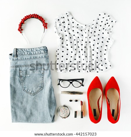 flat lay feminine clothes and accessories collage with shirt, jeans, glasses, mascara, lipstick, red high heel shoes, earrings and hoop on white background.