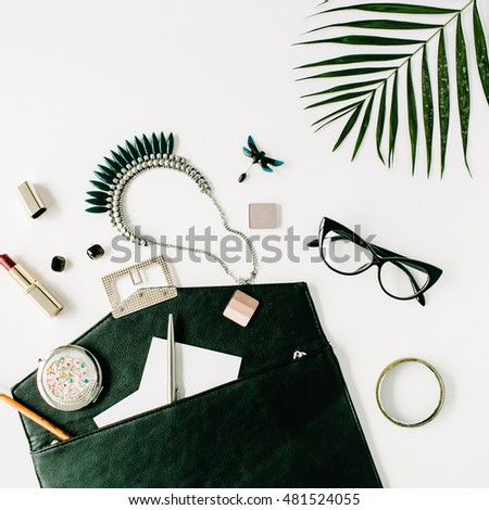 beauty feminine accessories arrangement with palm branch, purse, glasses, lipstick and necklace. flat lay, top view