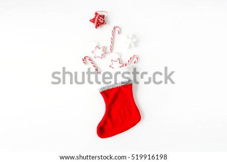 creative arrangement of bright red christmas toys in christmas sock on white background. flat lay, top view
