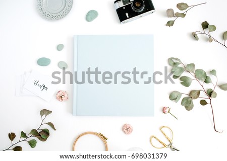 Blue family or wedding photo album  with blank space for text, eucalyptus leaf, retro camera and dry rose buds on white background. Flat lay, top view.