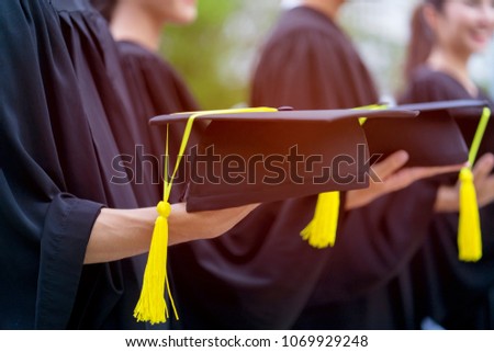 Group of newly graduated students holding graduation cap (hat) in hands during bachelor degree graduation ceremony from university, college with happiness, successful with certificate achievement