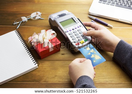Cashier hand holding a Credit card over EDC machine or credit card terminal with calculator and glasses. This is fake credit card.