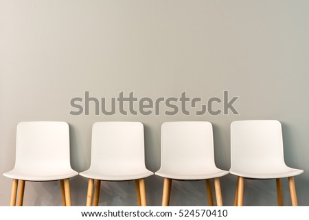 Chairs in modern design arranged in front of the gradient grey wall for interior or graphic backgrounds. The chairs can be used to represent interview sessions or waiting rooms for ads purpose.