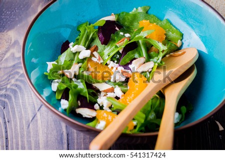 Delicious fruit and vegetables salad. Tangerine, beets, feta cheese, arugula and nut walnut in plate on wooden table background, top view with copy space. Healthy food concept.