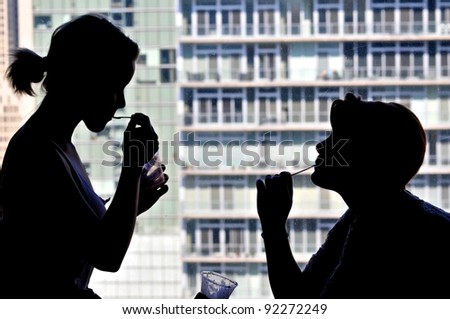 Silhouette of teen sisters having ice cream in hotel room