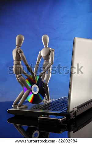 A couple of dummies bring in a software CD to a laptop.