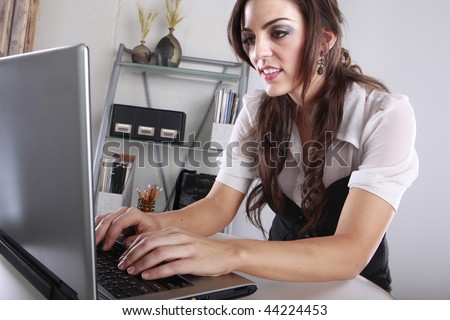 Young brunette entering data at her contemporary office