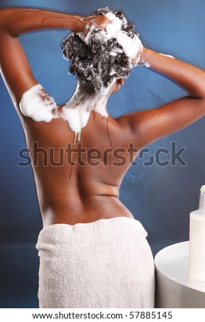 Cute African American washes her hair and turns her back to the camera