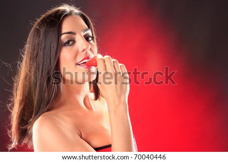 Hot brunette biting a fresh strawberry