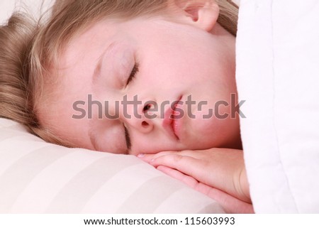 A little girl sleeping on a large white pillow