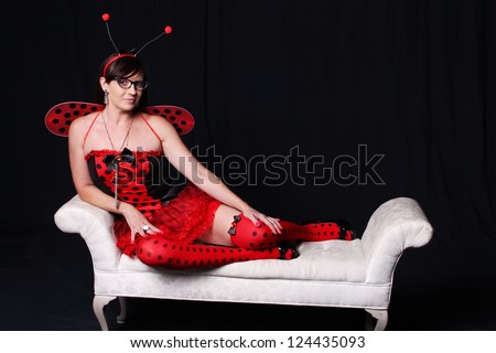 Woman dressed as a lady bug sitting on a white bench