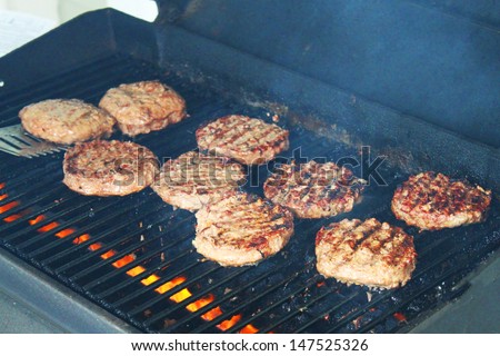 Delicious hamburger patties on a metal grill with fire under