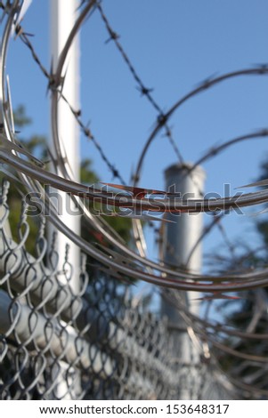Large metal fence with barbwire and razor wire