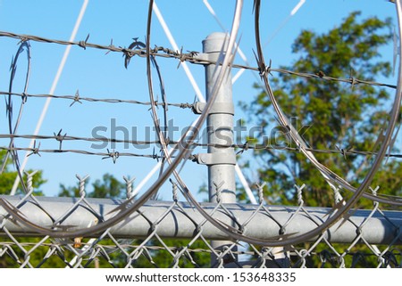 Large metal fence with barbwire and razor wire