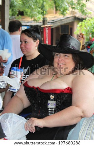 MUSKOGEE, OK - MAY 24: A woman dressed in historical costume and a hat enjoys the Oklahoma 19th annual Renaissance Festival on May 24, 2014 at the Castle of Muskogee in Muskogee, OK.