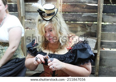 MUSKOGEE, OK - MAY 24: Woman dressed in vintage clothes makes jewelry at the Oklahoma 19th annual Renaissance Festival on May 24, 2014 at the Castle of Muskogee in Muskogee, OK