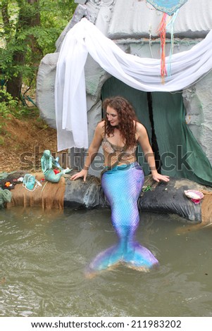 MUSKOGEE, OK - MAY 24: A woman dressed as a fairy mermaid shares treasures and smiles with kids at Oklahoma 19th annual Renaissance Festival on May 24, 2014 at the Castle of Muskogee in Muskogee, OK