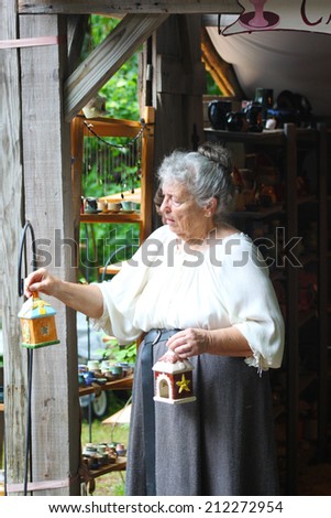 MUSKOGEE, OK - MAY 24: An old woman dressed in historical costume stops to show her craft at the Oklahoma 19th annual Renaissance Festival on May 24, 2014 at the Castle of Muskogee in Muskogee, OK.