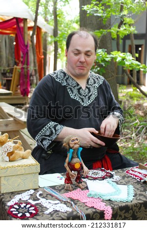 MUSKOGEE, OK - MAY 24: A man checks out a funny troll on his table during the Oklahoma 19th annual Renaissance Festival on May 24, 2014 at the Castle of Muskogee in Muskogee, OK.
