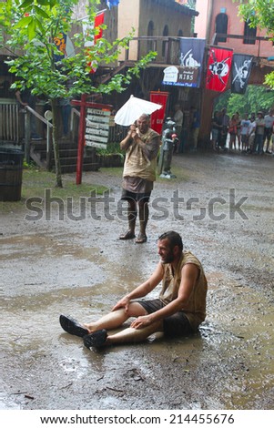 MUSKOGEE, OK - MAY 24: Grown men enjoy water and mud after rain at the Oklahoma 19th annual Renaissance Festival on May 24, 2014 at the Castle of Muskogee in Muskogee, OK.