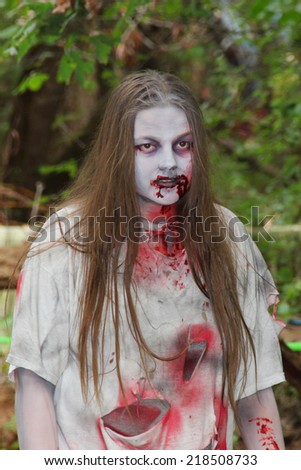 MUSKOGEE, OK - Sept. 13: Bloody zombies walk in the forest, waiting for athletes, during the Castle Zombie Run at the Castle of Muskogee in Muskogee, OK on September 13, 2014.