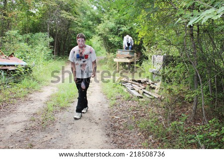 MUSKOGEE, OK - Sept. 13: Bloody zombies walk in the forest, waiting for athletes, during the Castle Zombie Run at the Castle of Muskogee in Muskogee, OK on September 13, 2014.