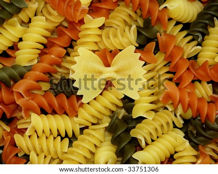 Twisted corkscrew pasta with one bow tie. Concept of being unique. background
