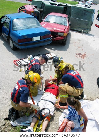 Police officers tend to car crash victims in a staged accident for training purposes