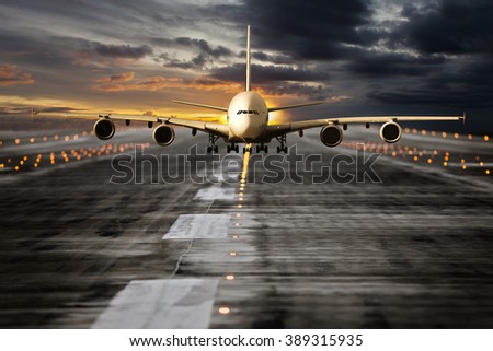 Large passenger plane runs along the airport runway during sunset time