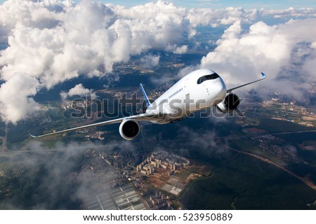 White passenger plane climbs through the clouds. Aircraft is flying high above the city.