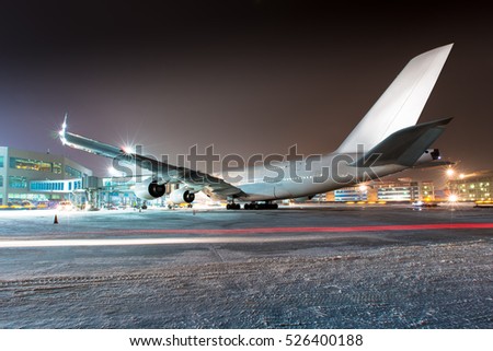 Double-decker passenger plane in preflight service. Aircraft parked near airport terminal at winter night. The airplane rear view.