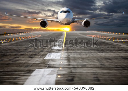A passenger plane takes off from the airport runway. Aircraft flies low over the airfield at sunset sky background. Airplane front view.